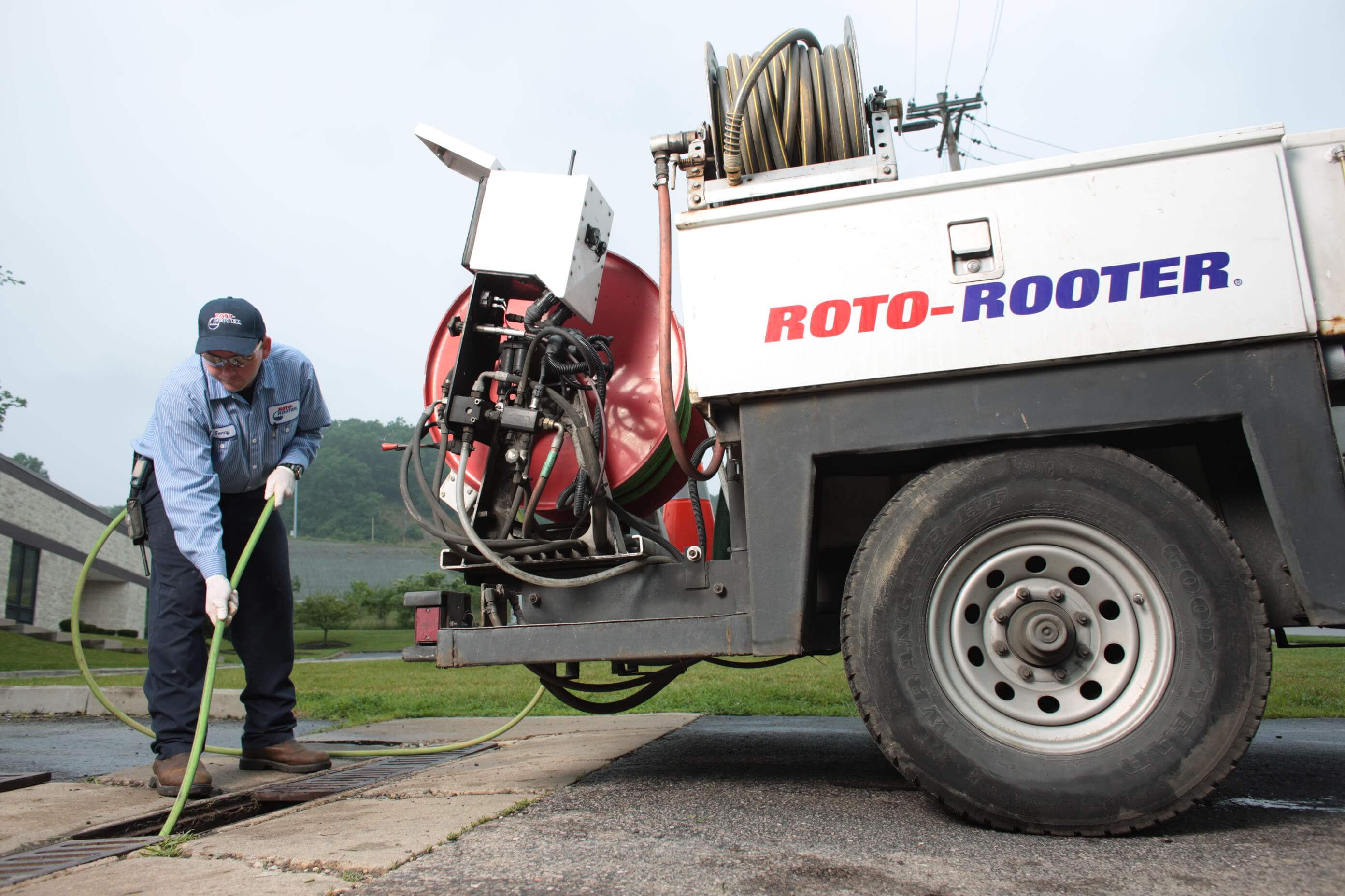 Plumber performing high-pressure water jetting service on sidewalk