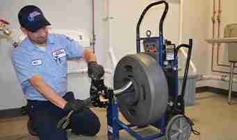 Roto-Rooter plumber using Drain Cleaning Machine to clear sewer line
