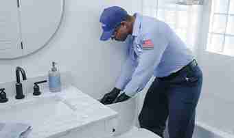 Roto-Rooter technician repairing toilet through tank